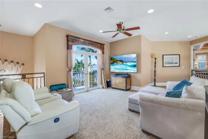 Carpeted living room with ceiling fan and french doors