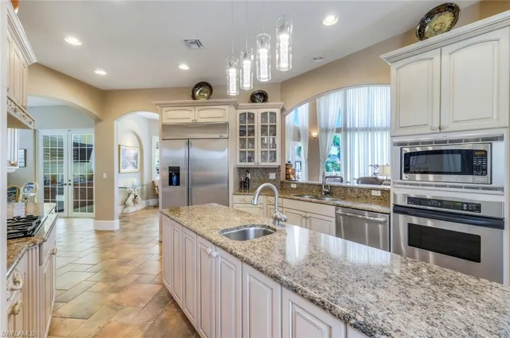 Kitchen featuring decorative light fixtures, sink, built in appliances, and light tile floors