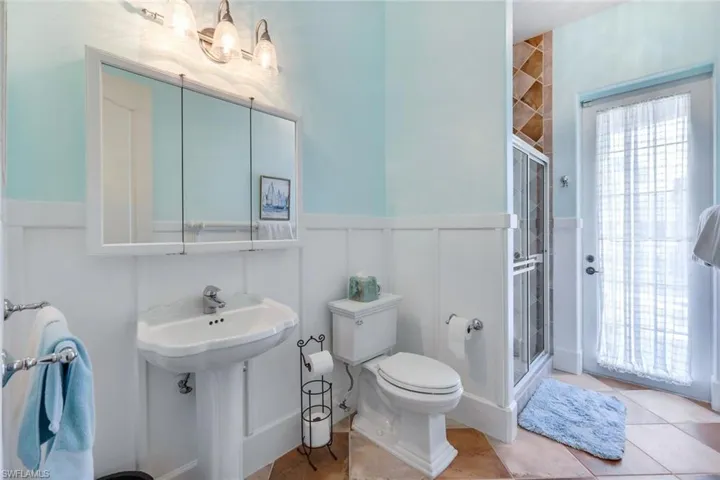Bathroom with tile floors, a shower with shower door, and toilet