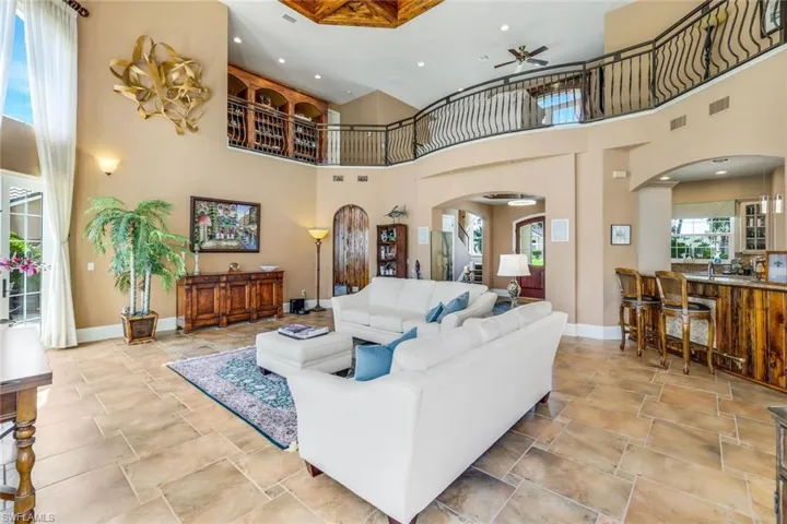 Living room with ceiling fan, a towering ceiling, and light tile flooring