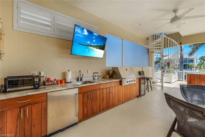 Outdoor Kitchen featuring ceiling fan, refrigerator, light stone countertops, sink, and light tile floors