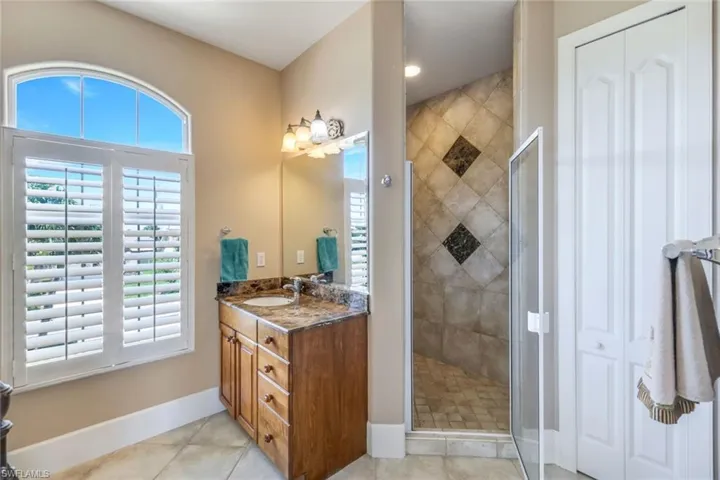 Bathroom featuring tile floors, a wealth of natural light, large vanity, and walk in shower