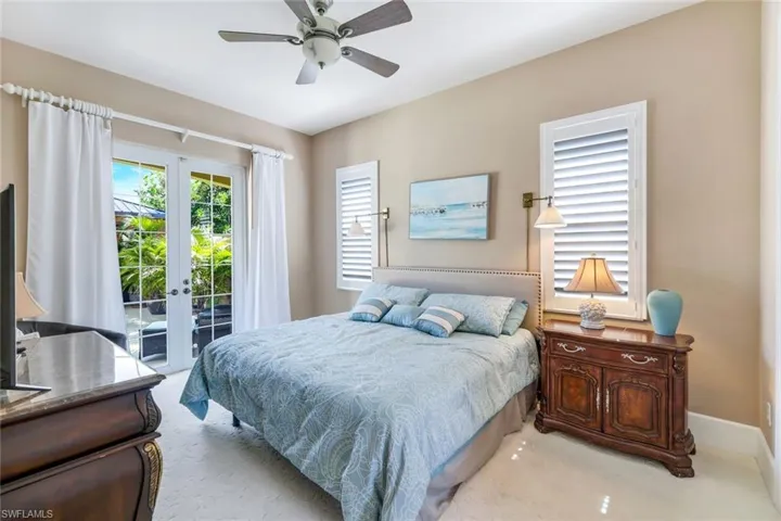 Carpeted bedroom featuring french doors, ceiling fan, and access to exterior