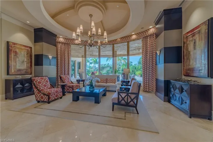 Tiled living room with a tray ceiling, a chandelier, and a high ceiling