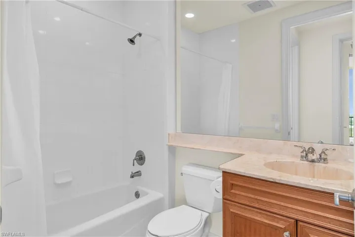 Full bathroom featuring shower / bathtub combination with curtain, toilet, and vanity