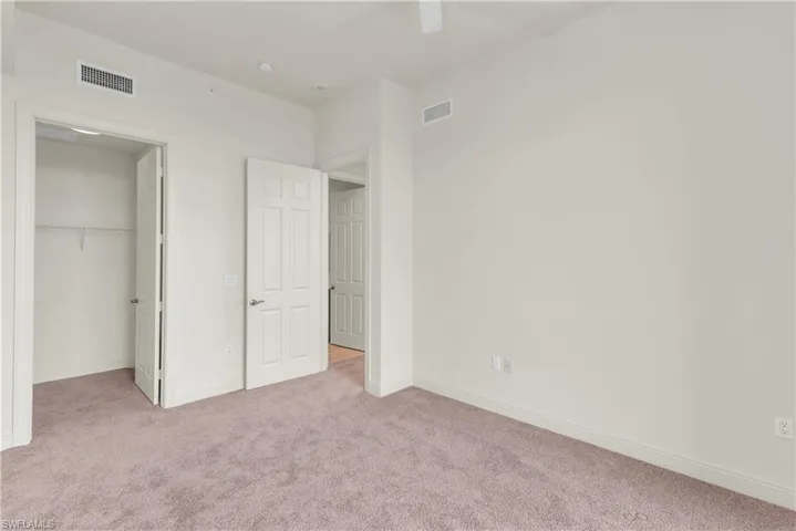 Unfurnished bedroom featuring ceiling fan, a closet, and light carpet