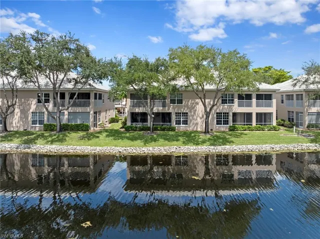 Back of property with a water view and a lawn