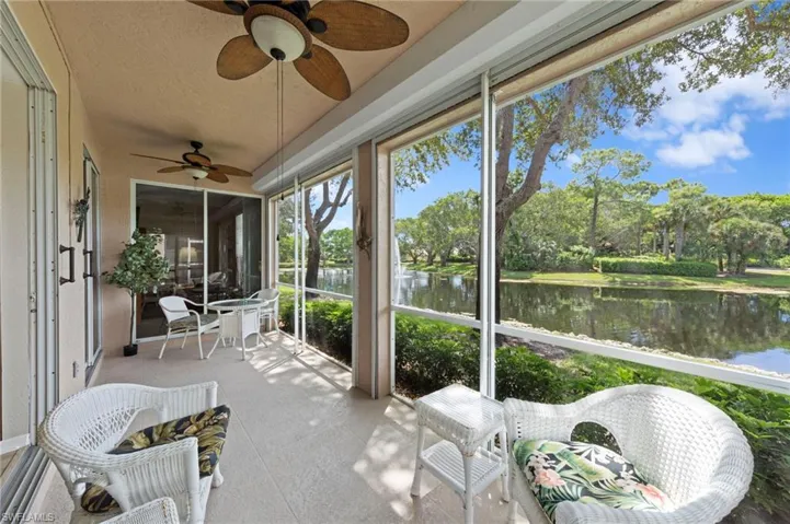 Sunroom with a water view, ceiling fan, and view of scattered trees