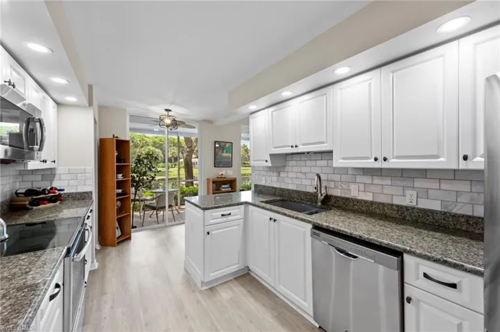 Kitchen with tasteful backsplash, a peninsula, appliances with stainless steel finishes, recessed lighting, and white cabinets