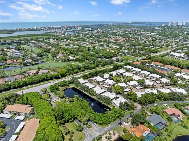 Aerial view of property and surrounding area with a nearby body of water and a tree filled landscape