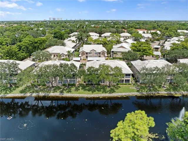 Aerial view of property and surrounding area with a nearby body of water and a tree filled landscape