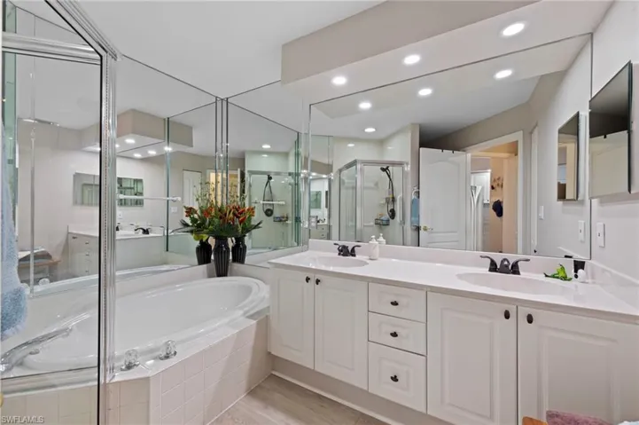 Bathroom featuring a stall shower, a garden tub, double vanity, recessed lighting, and light wood-style flooring
