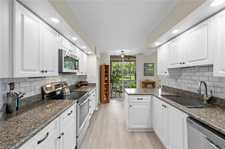 Kitchen featuring tasteful backsplash, appliances with stainless steel finishes, dark stone counters, recessed lighting, and white cabinetry
