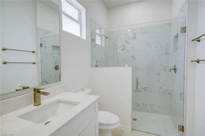 Bathroom with tile patterned floors, vanity, walk in shower, and toilet