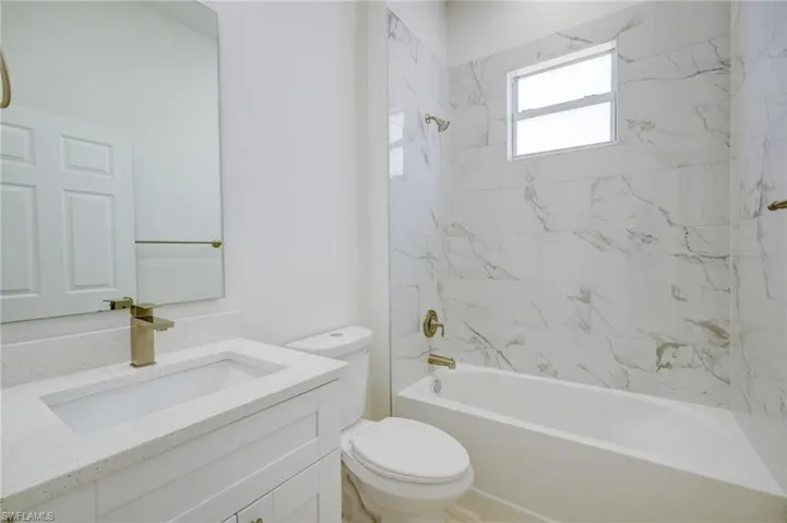 Full bathroom with vanity, tiled shower / bath, and toilet
