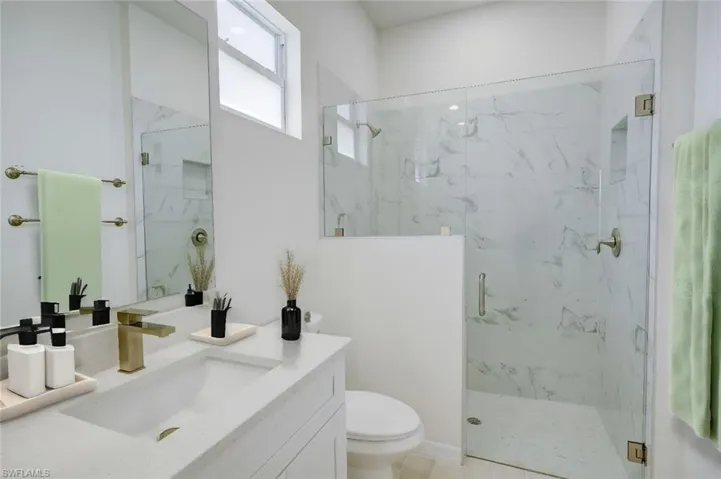 Bathroom featuring walk in shower, tile patterned flooring, toilet, and vanity