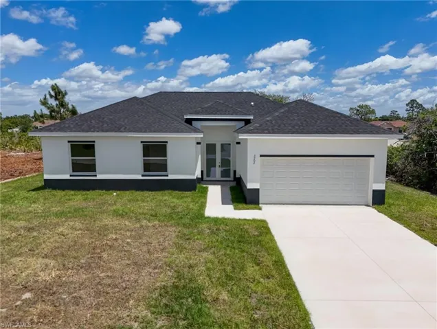 View of front of property with a garage and a front lawn