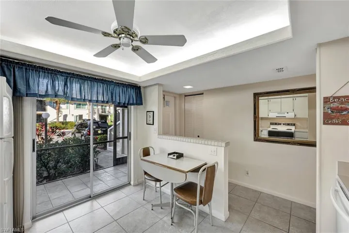 Dining room featuring light tile patterned floors, ceiling fan, and a raised ceiling