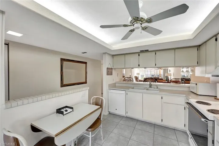 Kitchen with light countertops, a tray ceiling, white appliances, and light tile patterned floors