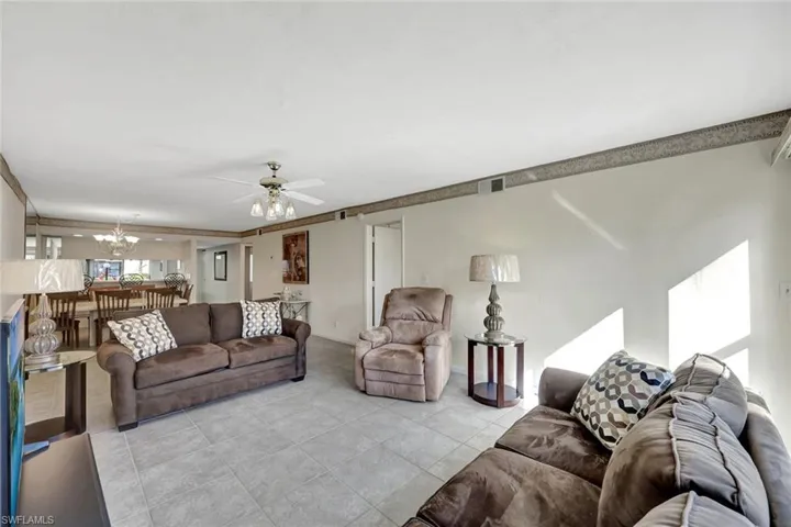 Living area with tile patterned flooring, a ceiling fan, and a chandelier