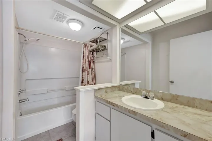 Full bath featuring shower / bath combo, vanity, and light tile patterned flooring