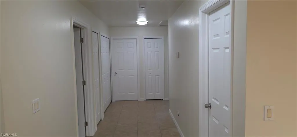 Corridor featuring light tile patterned flooring and baseboards