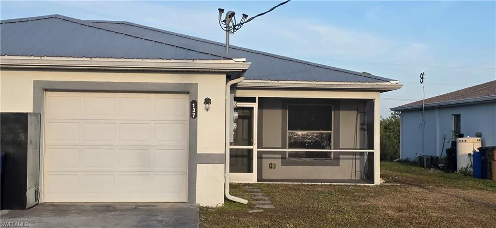 View of front of house with a sunroom, a metal roof, driveway, and a front lawn