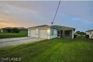 View of front of property featuring driveway, a sunroom, a front yard, and an attached garage