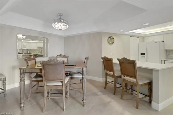 Kitchen with white appliances, white cabinets, sink, light tile patterned floors, and a tray ceiling