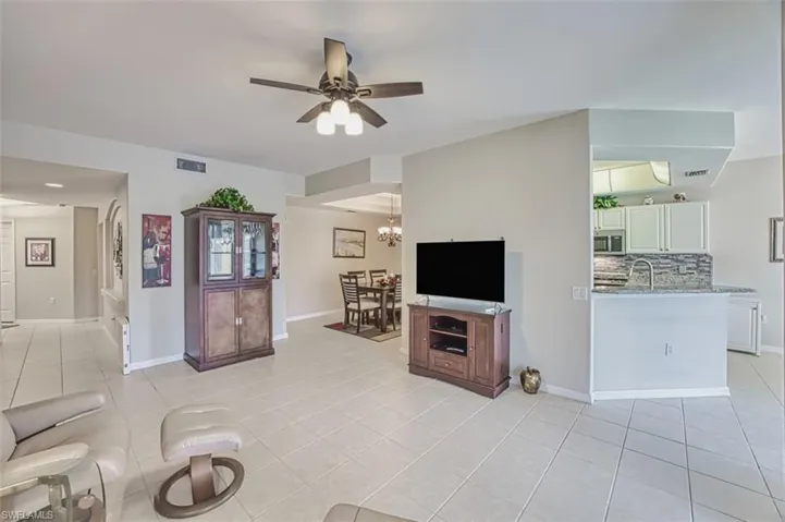 Living room featuring light tile patterned floors, a ceiling fan, and baseboards