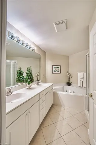 Full bath with a garden tub, tile patterned flooring, a shower stall, and double vanity