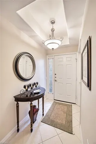 Entryway with a raised ceiling, light tile patterned floors, and baseboards