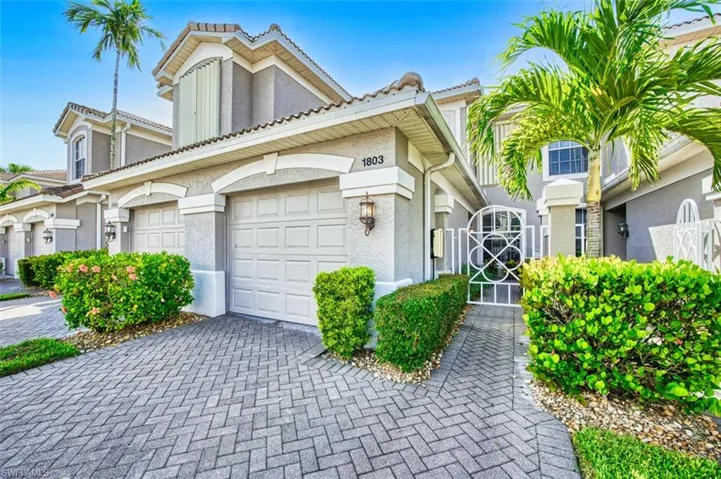 Townhome / multi-family property featuring stucco siding, a garage, driveway, a tiled roof, and a gate