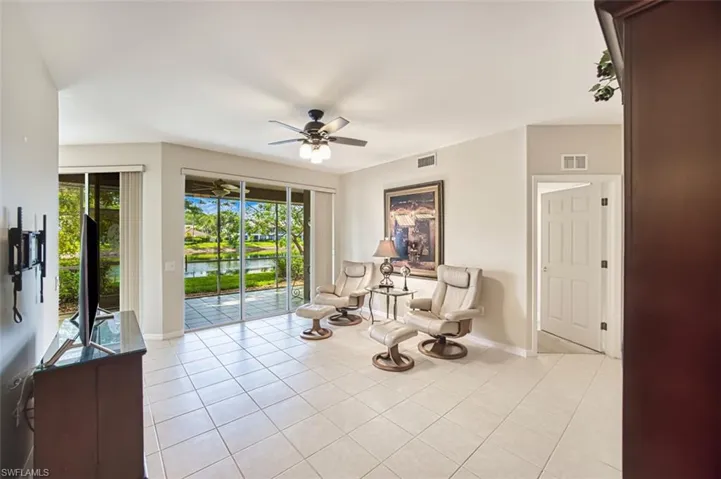 Living area featuring a ceiling fan, light tile patterned floors, and baseboards