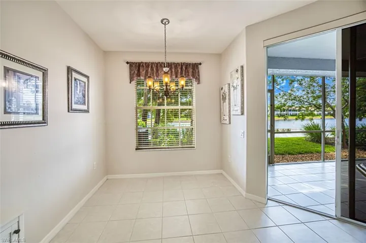 Unfurnished dining area with a water view, a chandelier, light tile patterned flooring, and baseboards