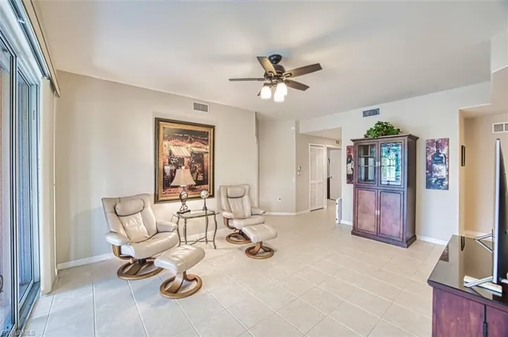 Living area featuring ceiling fan, light tile patterned floors, and baseboards