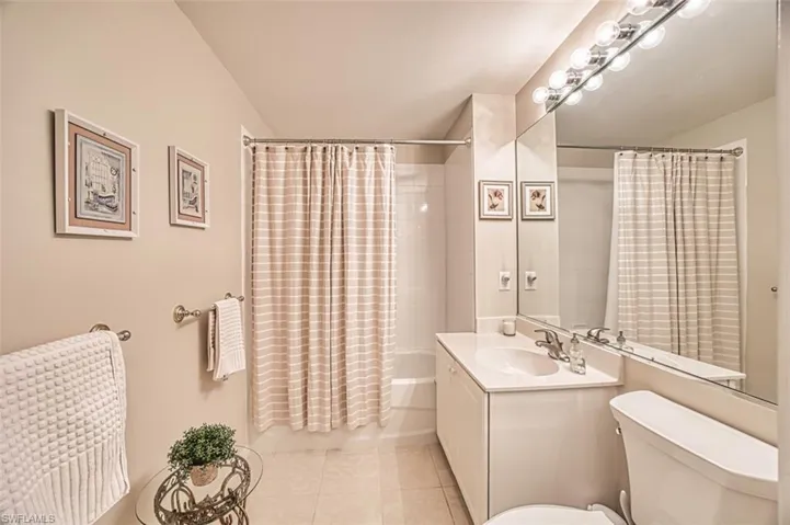 Bathroom featuring toilet, vanity, tile patterned floors, and shower / bathtub combination with curtain