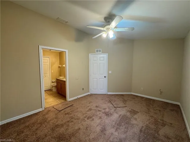 Unfurnished bedroom with light carpet, connected bathroom, lofted ceiling, and ceiling fan