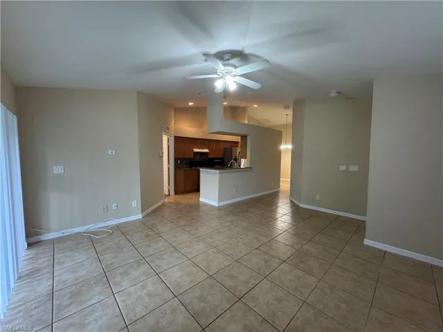 Unfurnished living room featuring light tile patterned floors, a ceiling fan, and lofted ceiling