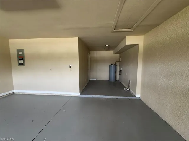 Garage featuring baseboards and electric water heater