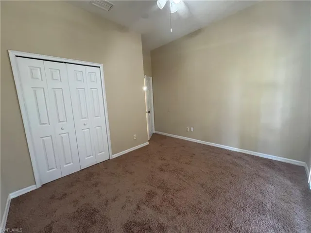 Unfurnished bedroom featuring carpet floors, a closet, and a ceiling fan
