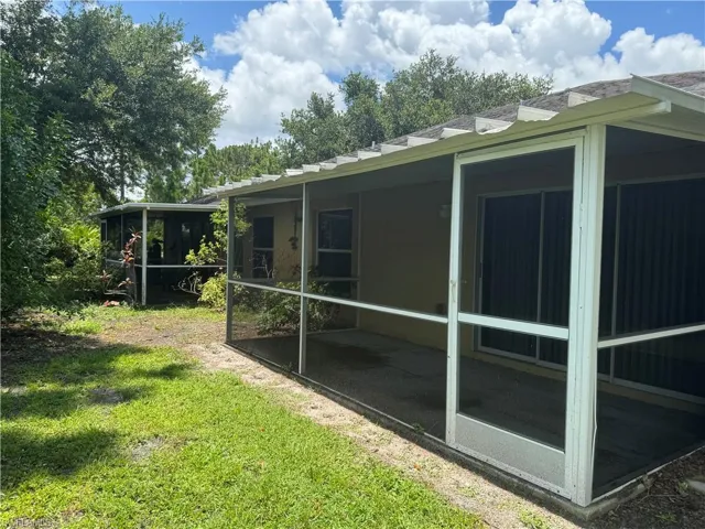 View of property exterior featuring a sunroom and a lawn