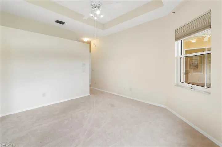 Recessed lighting accents the tray ceiling with a central ceiling fan