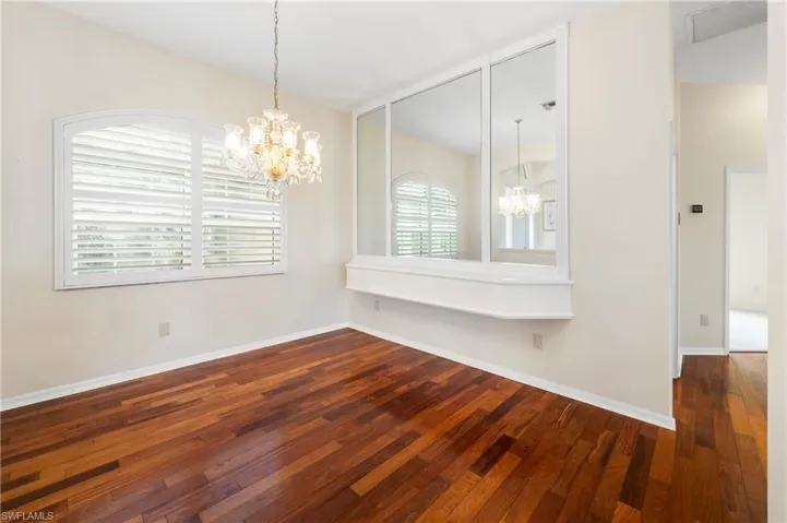 Spacious room featuring rich wood-finish flooring and a crystal chandelier