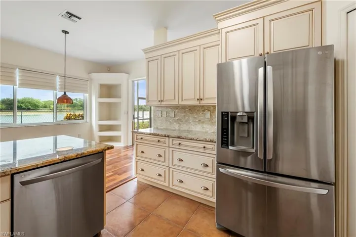 Kitchen featuring abundant cream-colored cabinetry, stainless steel appliances, and granite countertops
