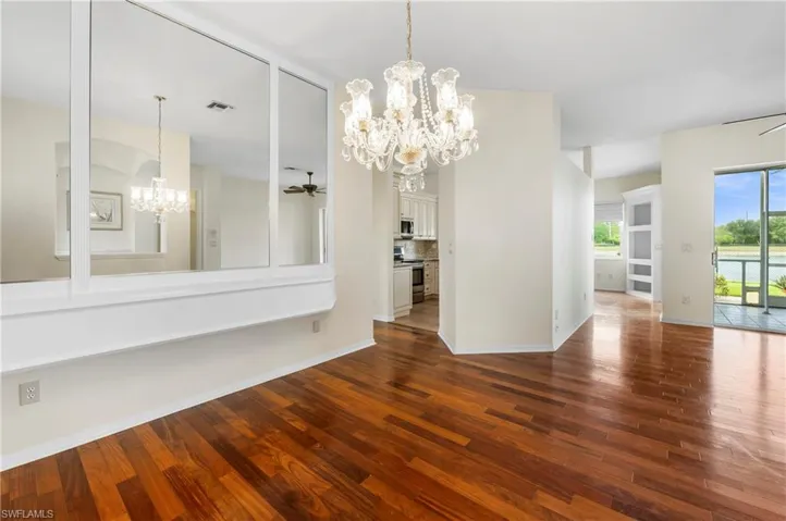 Rich wood-finish flooring complements the interior space featuring a multi-paneled mirror accent wall and a prominent chandelier