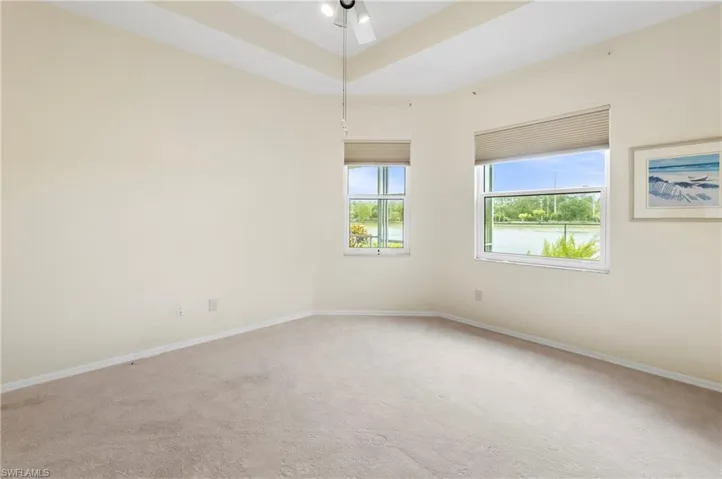 Carpeted room featuring multiple windows with blinds, a vaulted ceiling, and an overhead ceiling fan