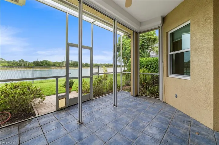 Screened patio featuring blue-toned tile flooring, a beige stucco exterior wall, and a ceiling fan