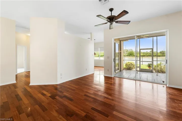 Expansive living area with wood-finish flooring, a ceiling fan, and direct access to a screened lanai