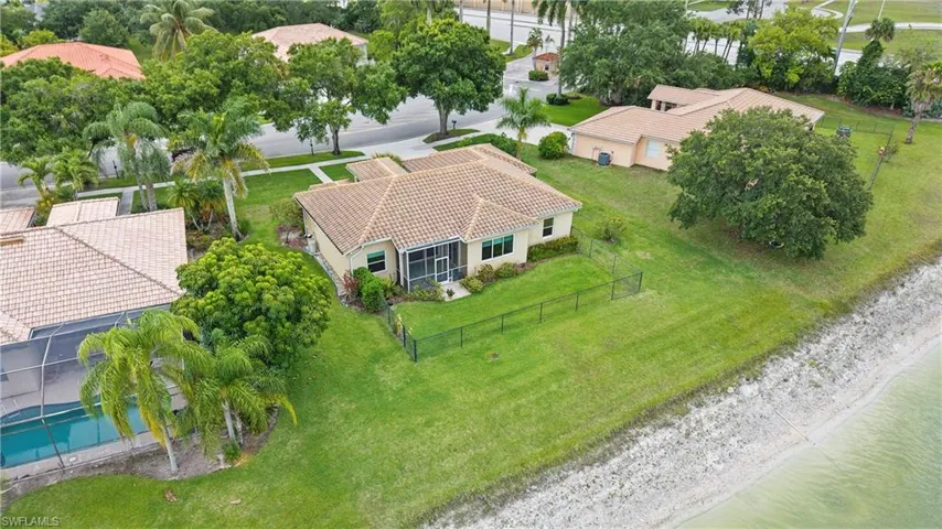 Waterfront property featuring a screened-in lanai, tile roof, and a private rear fence